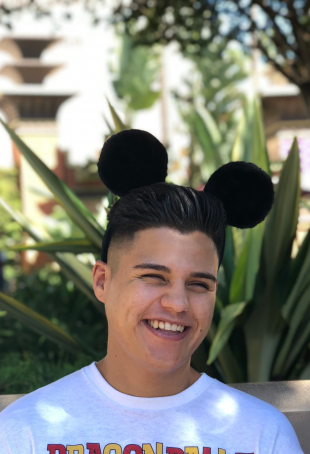 Julian smiling at the camera wearing black Mickey Mouse ears.