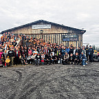 A group photo of the attendees beneath the Arctic Village sign.