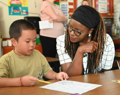 Dr. Charlene Williams sitting with a student in a classroom.